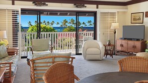 A room with a balcony, wicker furniture, a television, and a view of the ocean. - Kiahuna Plantation Resort Partial Ocean 2 Bedroom (Koloa)