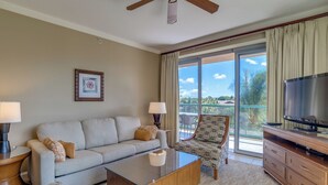 A hotel room with a sofa, armchair, coffee table, TV, and a balcony with a view. - Honua Kai Resort View 2 Bedroom (Lahaina)