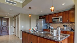A modern kitchen with wooden cabinets, stainless steel appliances, and a granite countertop. - Honua Kai Resort View 2 Bedroom (Lahaina)
