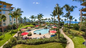 A resort pool area with a curved pool, palm trees, and lounge chairs.
