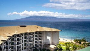 A multi-story hotel with a view of the ocean and a mountain in the distance.