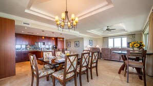 A spacious living area with a dining table, chairs, and a kitchen in the background.