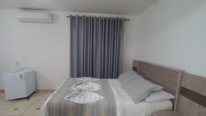 Un dormitorio con cama, mesita de noche, aire acondicionado de pared y luz de techo.