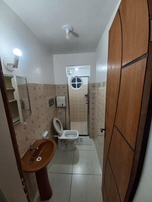 Ein kleines Badezimmer mit Toilette, Waschbecken und Spiegel.