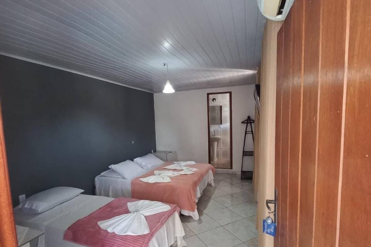 Une chambre d’hôtel avec deux lits, une armoire en bois, un sol carrelé et un plafond doté d’un luminaire.