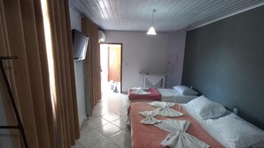 Een hotelkamer met twee bedden, een aan de muur bevestigde televisie en een plafondventilator.