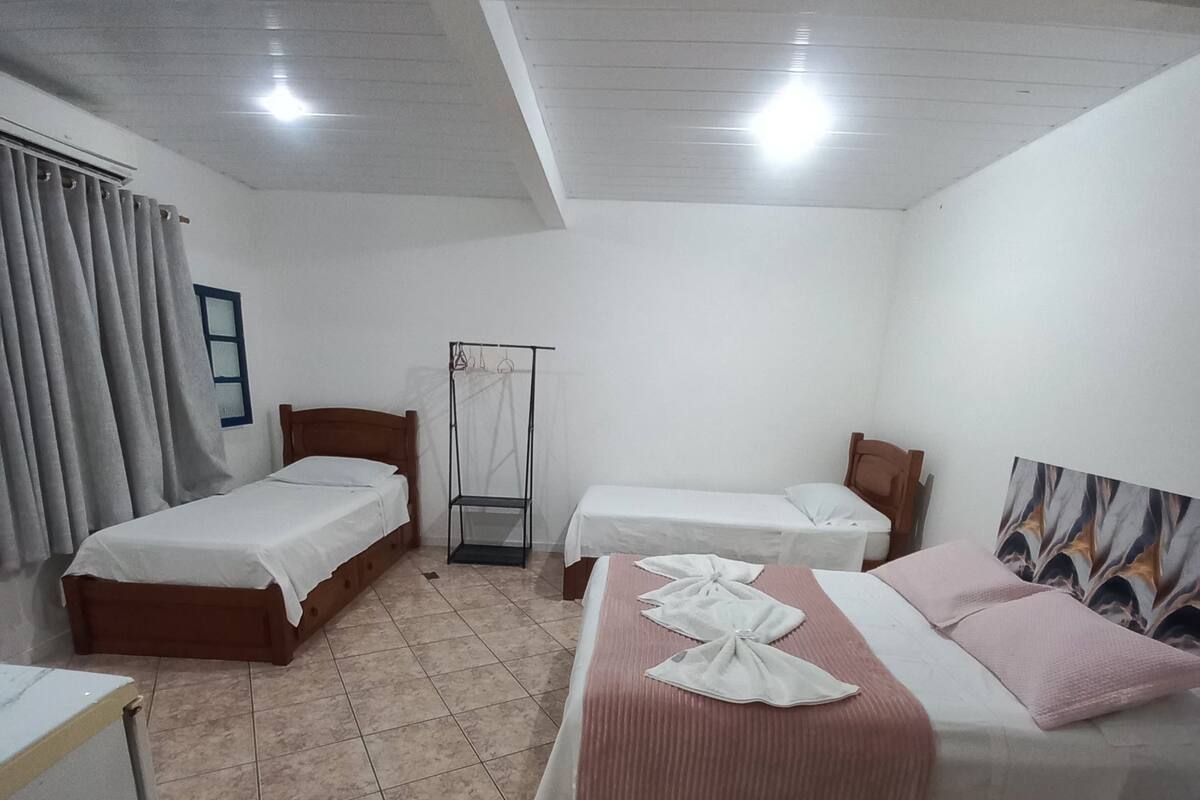 Une chambre d’hôtel avec deux lits simples, un lit double, une armoire, un bureau et un miroir.