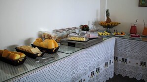 Una mesa de buffet con diversos alimentos y bebidas, como pan, pasteles, frutas y una piña.