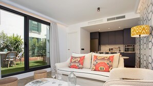 A modern living room with a sofa, a coffee table, and a dining area visible through a large sliding glass door. - Genteel Home Casa Lagar III (Seville)