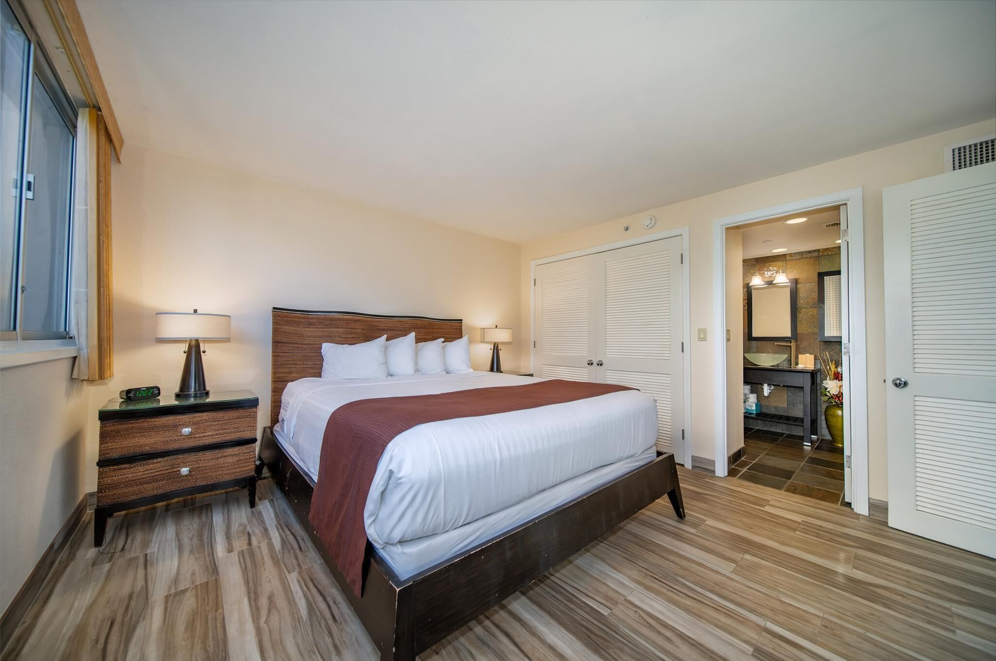 Une chambre à coucher bien rangée, avec un grand lit, des tables de chevet et une petite table de nuit.