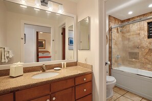 A bathroom with a sink, mirror, and shower.