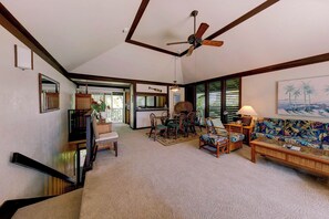 A spacious living area with a high ceiling, a ceiling fan, and a dining area with chairs and a table. - Kiahuna Plantation Resort Royal Garden 2 Bedroom (Koloa)