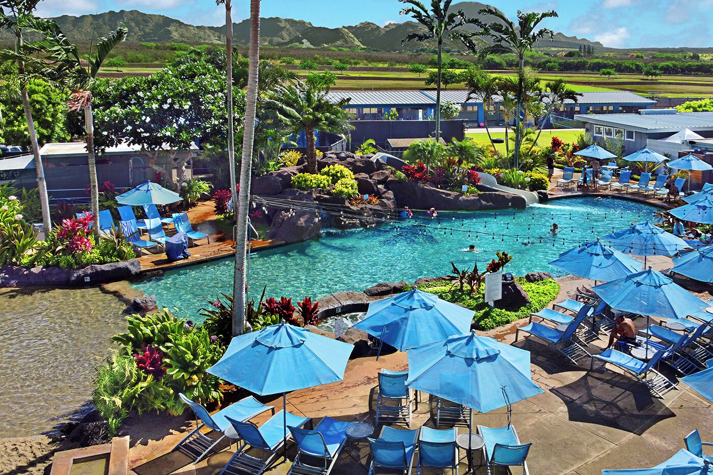 Un resort con piscina, sillas de descanso y sombrillas.