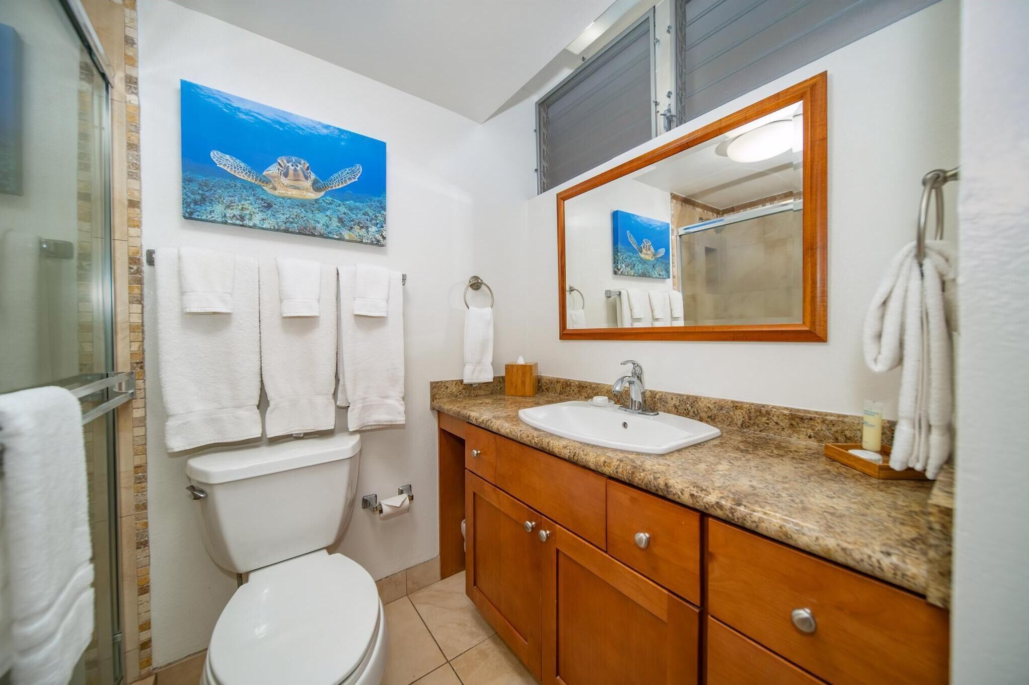 A bathroom with a toilet, sink, vanity, and a large mirror.