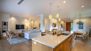 A modern kitchen with a central island, wooden cabinetry, and pendant lighting.