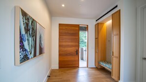 A hallway with wooden flooring, a wooden door, and a bench with a patterned cushion.