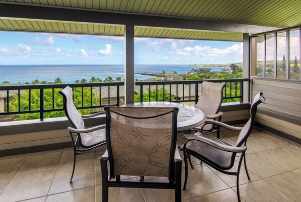 A covered outdoor seating area with a view of the ocean.