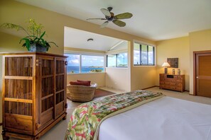 Une chambre à coucher comprenant un lit, une armoire en bois, un ventilateur de plafond, une fenêtre avec vue et une commode.