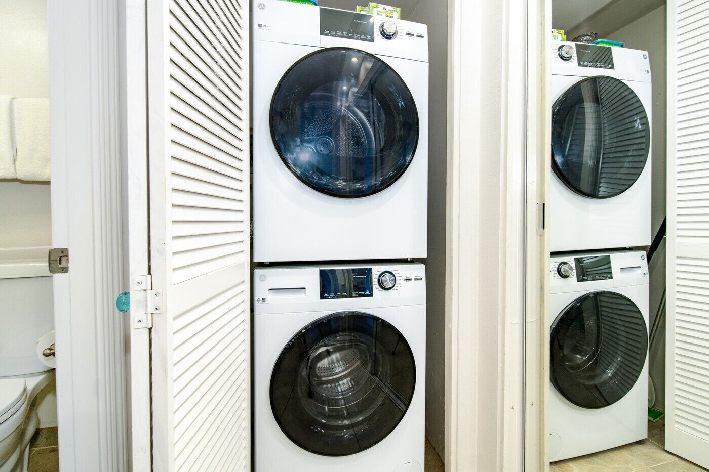 Une buanderie équipée de machines à laver et de sèche-linge à chargement frontal, disposés les uns au-dessus des autres.