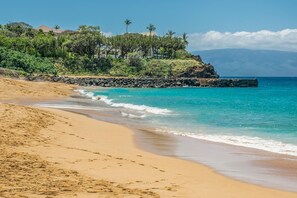 A sandy beach with clear turquoise water, a rocky breakwater, and lush greenery. - Kaanapali Maui Eldorado A106 Partial Ocean 1 BD (Lahaina)