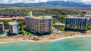 Un complejo turístico costero con varios edificios altos, una playa y montañas al fondo.