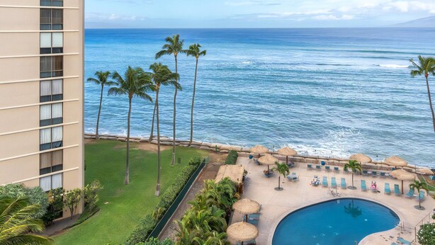 Un hôtel doté d’une piscine, de palmiers et offrant une vue sur l’océan.