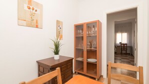 Un comedor con una mesa de madera, sillas, un armario con puertas de cristal y una planta en maceta.