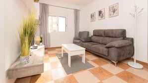 Una sala de estar con un sofá, una mesa de centro, una lámpara de pie y una planta en maceta.