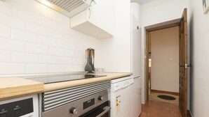 A compact kitchen with white tiles, a wooden countertop, a dishwasher, and an oven. - El Cortijo in La Linea de la Conception (La Línea de la Concepción)