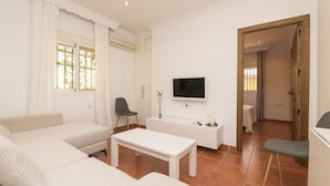 A modern living room with a sofa, a coffee table, a TV, and a small side table. - El Cortijo in La Linea de la Conception (La Línea de la Concepción)