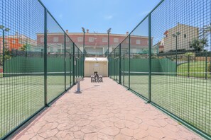 A tennis court with a net, a seating area with benches, and a trash bin. - Las Cumbres in Islantilla (Lepe)