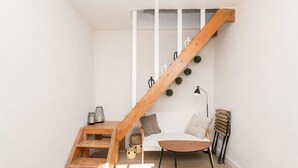 A staircase with a wooden handrail, a white wall, a cushioned bench, a small wooden table, and a floor lamp. - Pura Vida in Vejer de la Frontera (Vejer de la Frontera)