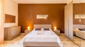 A bedroom with a large bed, wooden headboard, bedside tables with lamps, a wardrobe, and a mirror. - Villa With Volcano View (Zafferana Etnea)