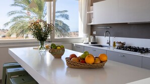Et moderne køkken med en stor ø, en skål med frugt og en vase med blomster.