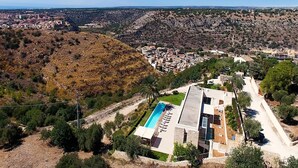Et boligområde med swimmingpool, moderne huse og et kuperet landskab.