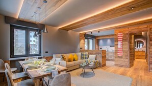A modern interior with a dining area, sofa, and kitchen. - Simona Luxuryapartment few Steps From ski (Sestriere)