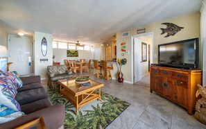 A living room with a sofa, coffee table, TV, and dining area with chairs and a table.
