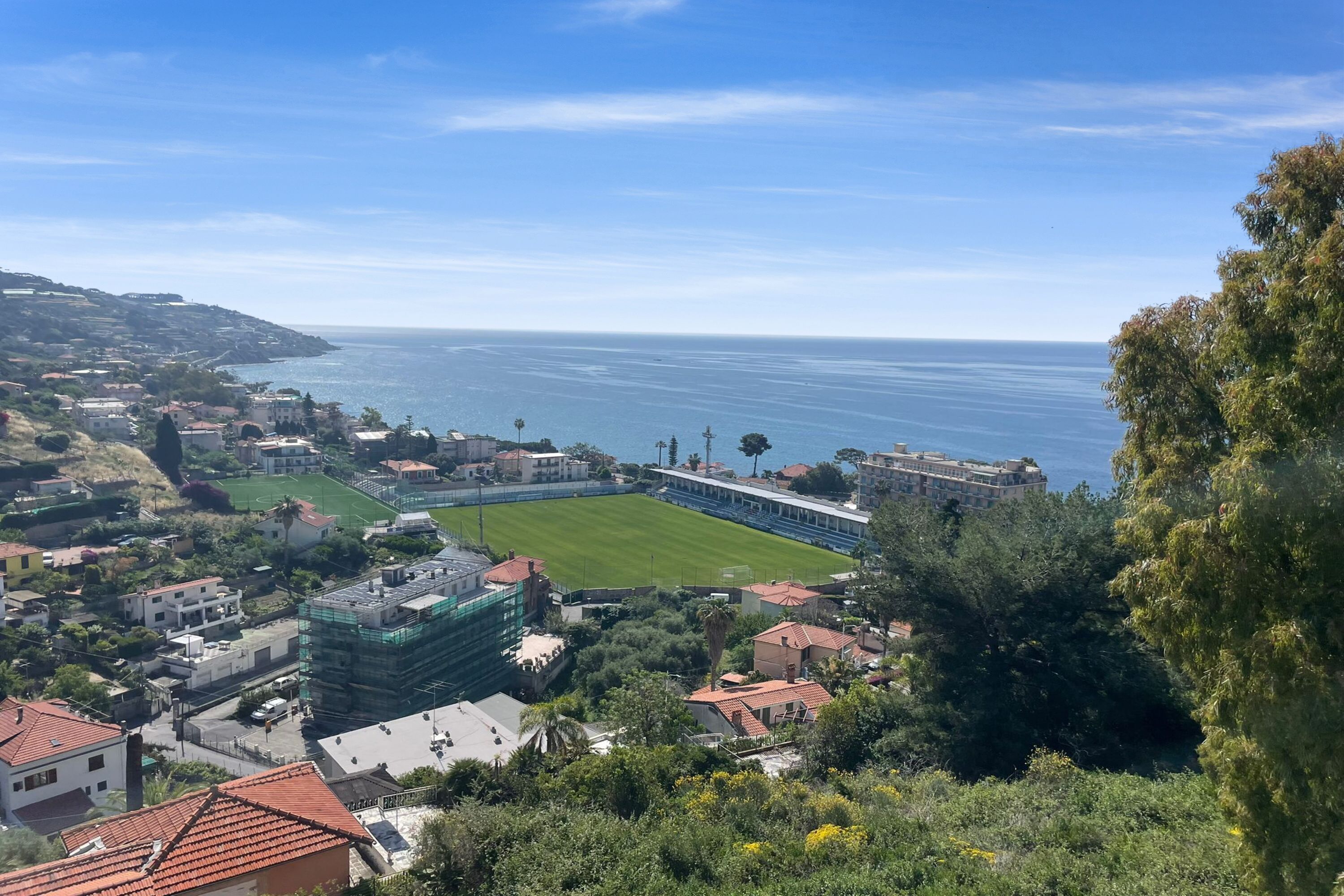 A coastal town with a stadium, residential buildings, and a view of the sea.