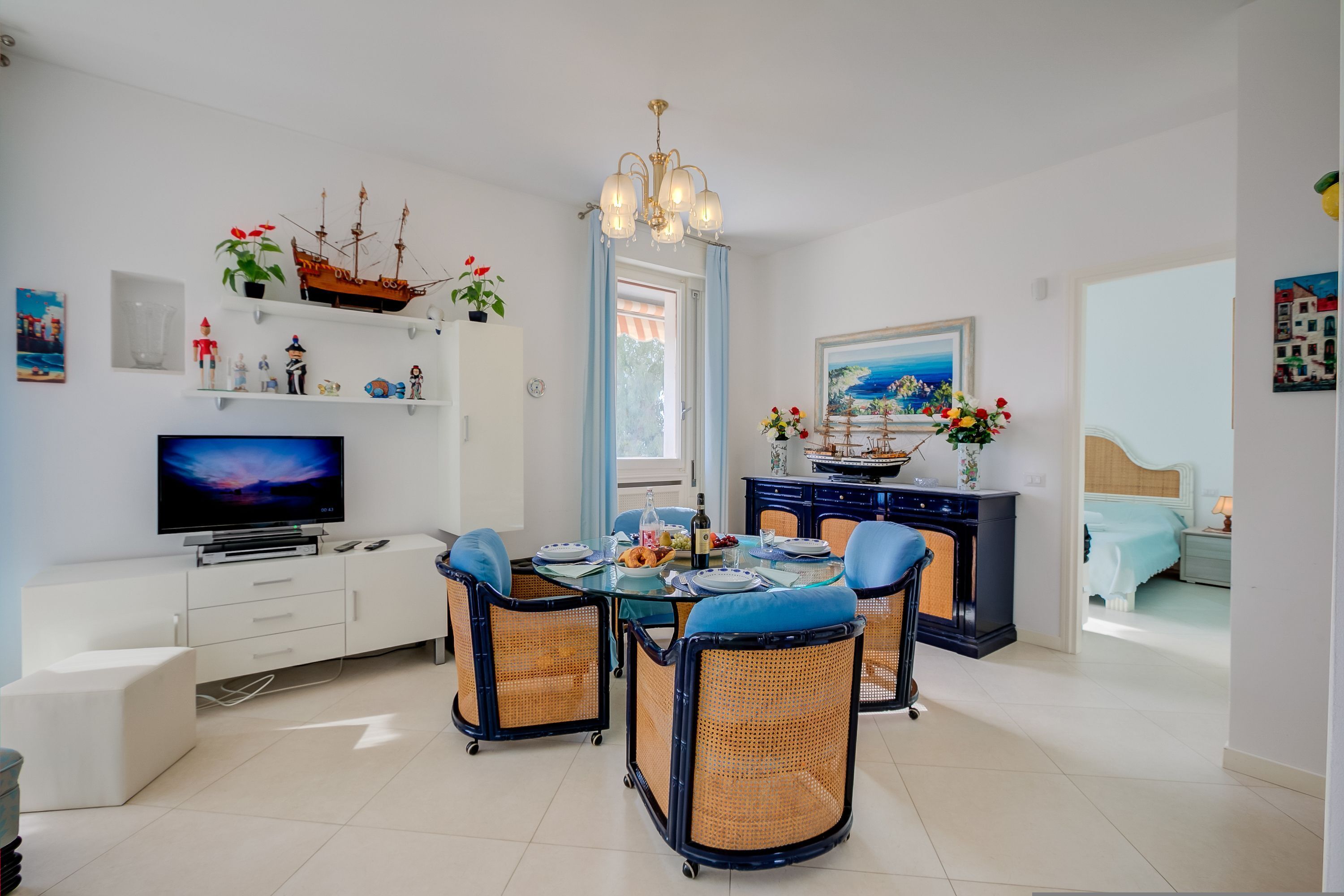 A modern living room with a dining area, a television, and decorative items on shelves.