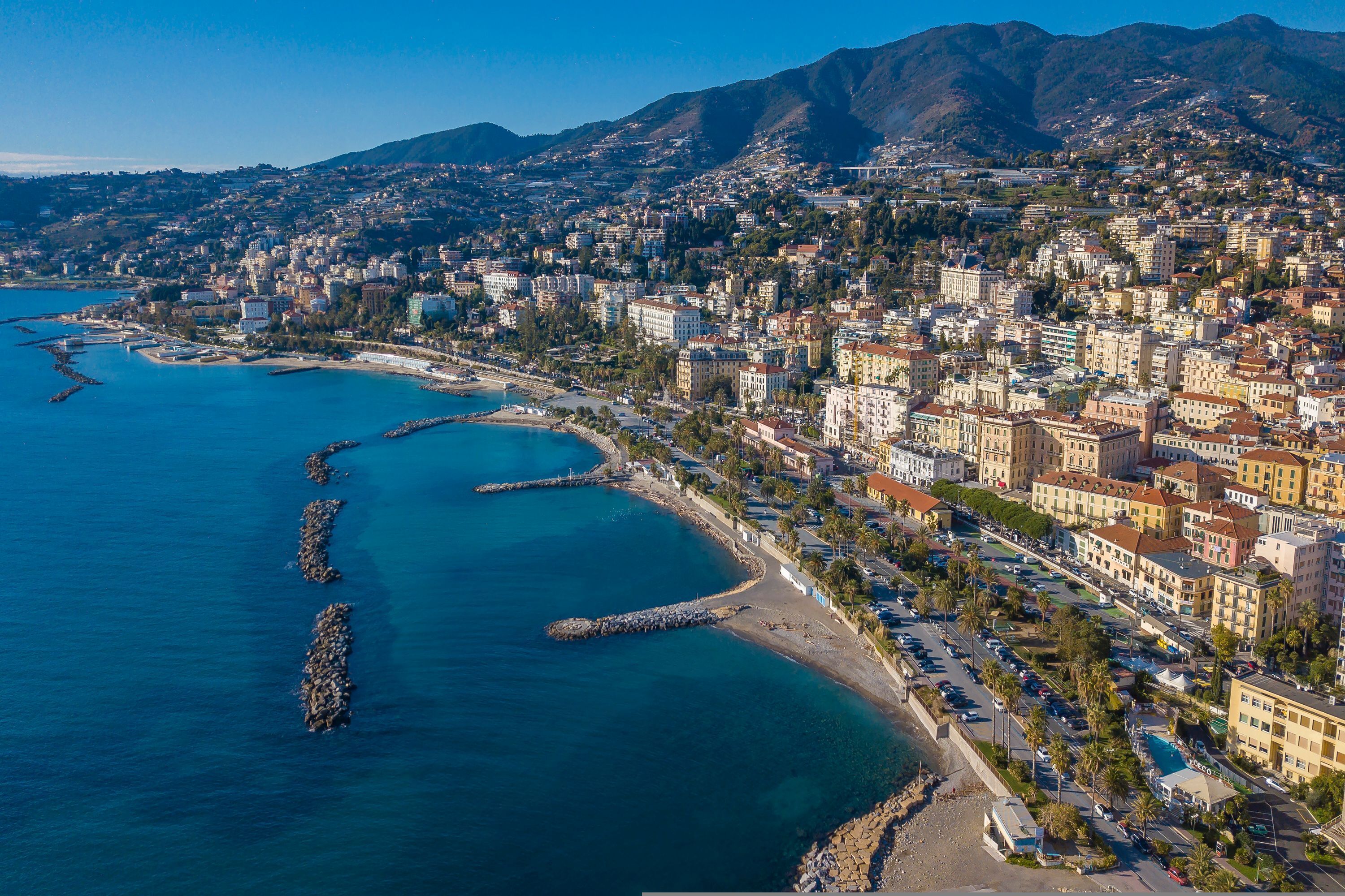 A coastal cityscape with a prominent beach and rocky breakwaters.
