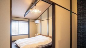 A room with a bed, a window, and a wall-mounted air conditioner. - Kyomachi Rakunan (Kyoto)