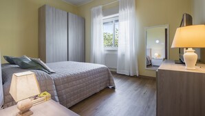 A hotel room with a bed, a nightstand with a lamp, a dresser, a mirror, and a window with curtains. - Pedara Escape With Garden by Wonderful Italy (Pedara)