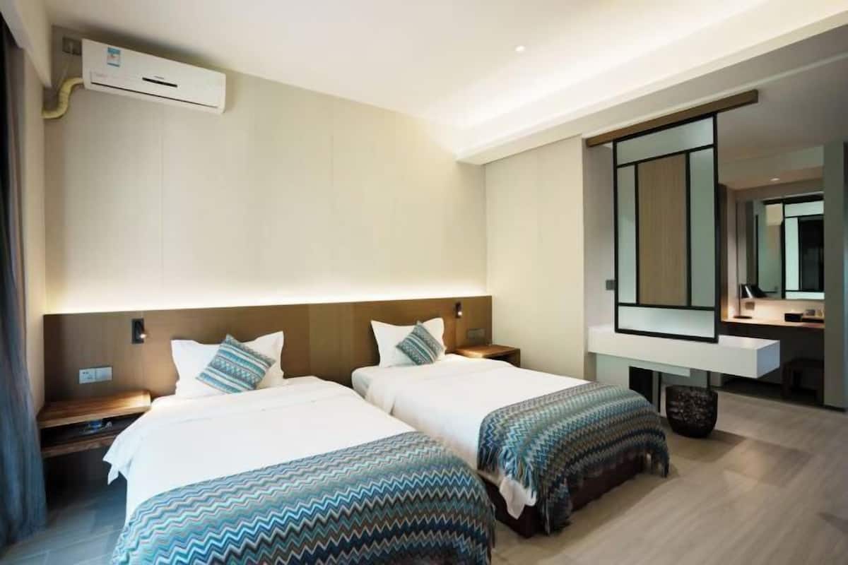 A hotel room with two beds, a large mirror, a desk, and a modern design.