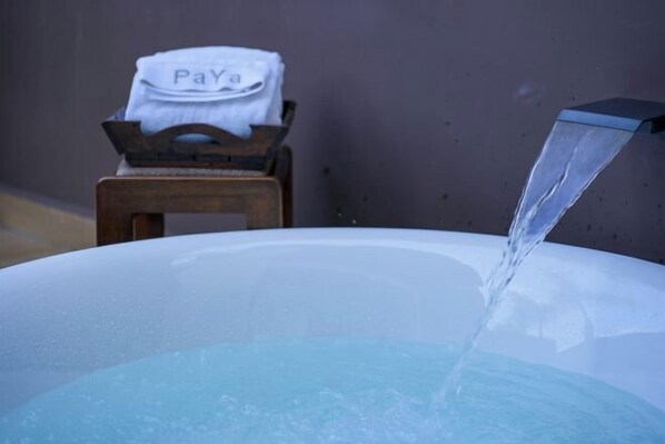 A hot tub with a towel labeled "Pay Here" on a wooden stool beside it. - Nanlahe Paya Resort Hotel (Mengla)