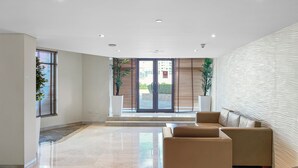 A spacious lobby with a modern design, featuring a large seating area, a glass door entrance, and a decorative wall.