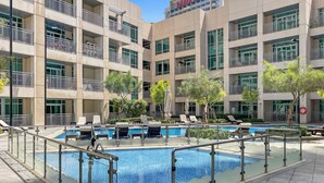 A modern hotel with a pool area, multiple balconies, and outdoor seating.