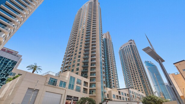 A high-rise building with a modern architectural design, featuring multiple balconies and large windows.