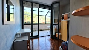 A modern room with a large sliding glass door leading to a balcony, a small table, and a bed with a star-patterned blanket. - Como Apartment + Free parking & WiFi (Como)