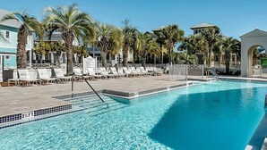 A pool area with lounge chairs, palm trees, and a clear blue pool. - Relax Awhile (Panama City Beach)