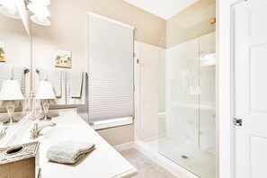 Enjoy a refreshing shower in this sleek bathroom with a glass enclosure, sink, and ample mirror space.
